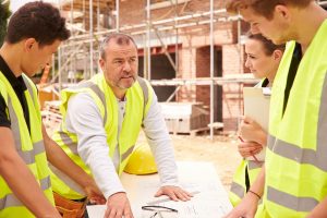 four workers on a builiding site looking at plans